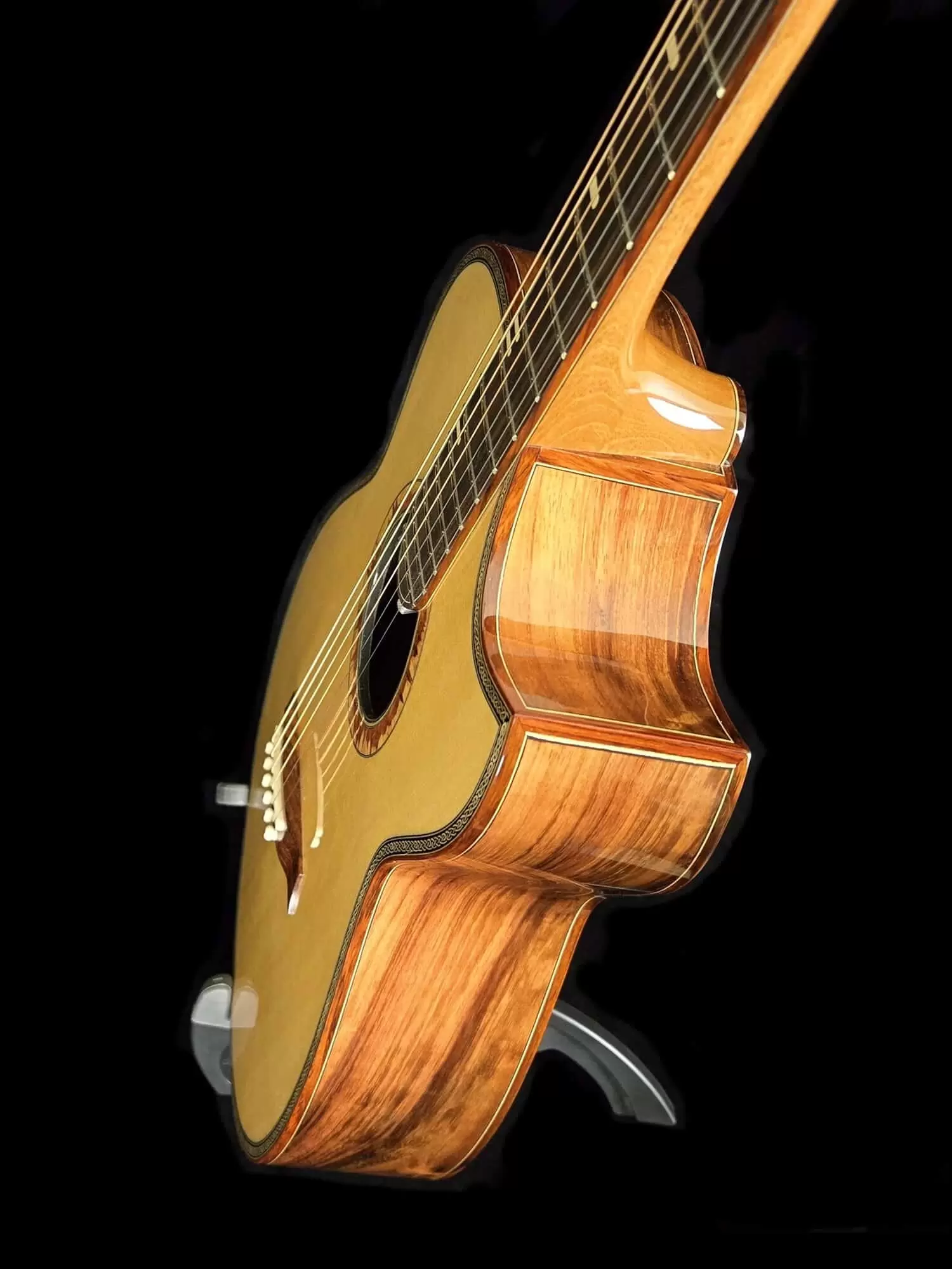 Angled side view of an acoustic guitar showing the body depth, wood grain sides, and neck joint.