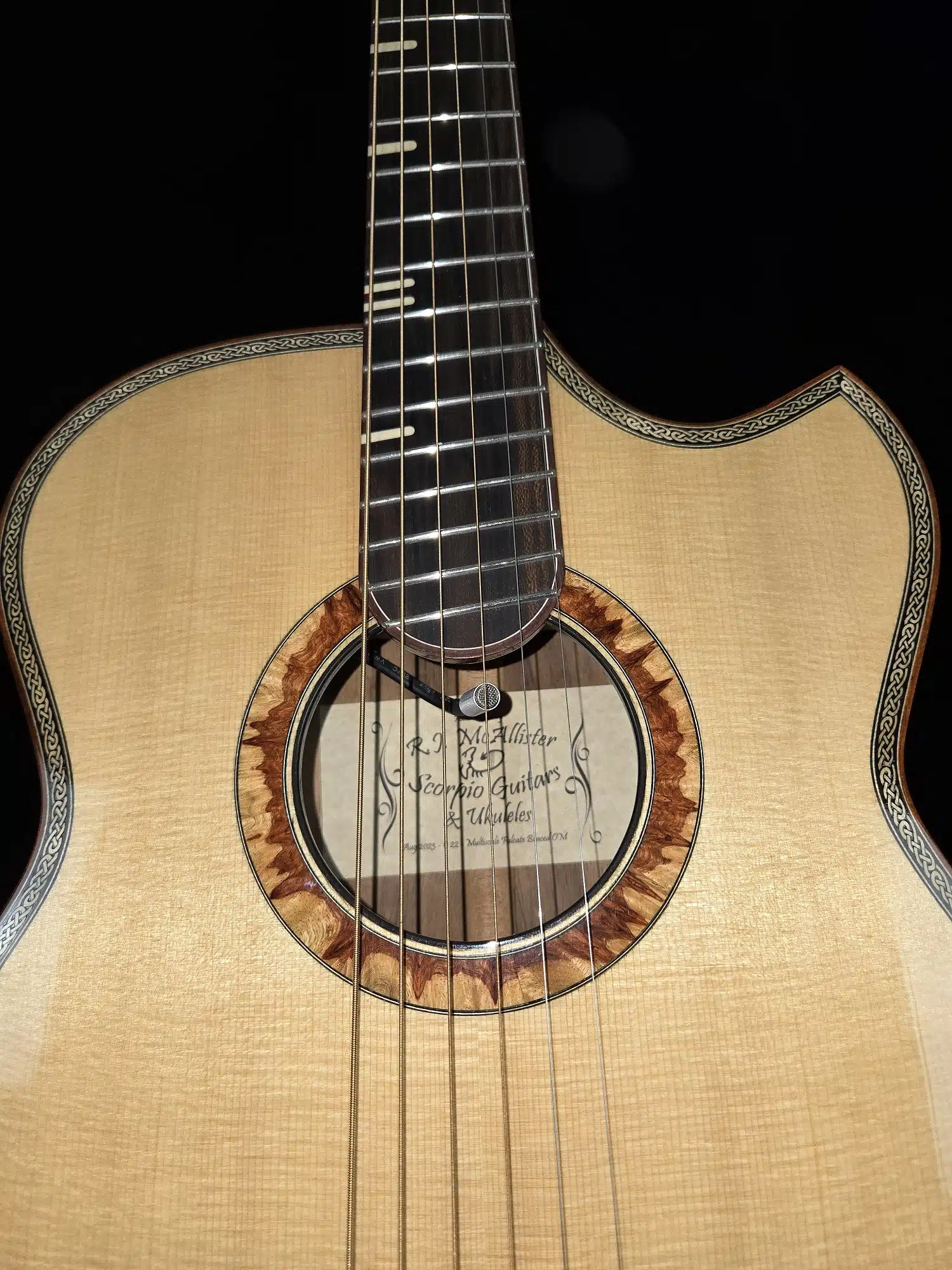 Close-up of an acoustic guitar soundhole with decorative rosette, strings, and fretboard.