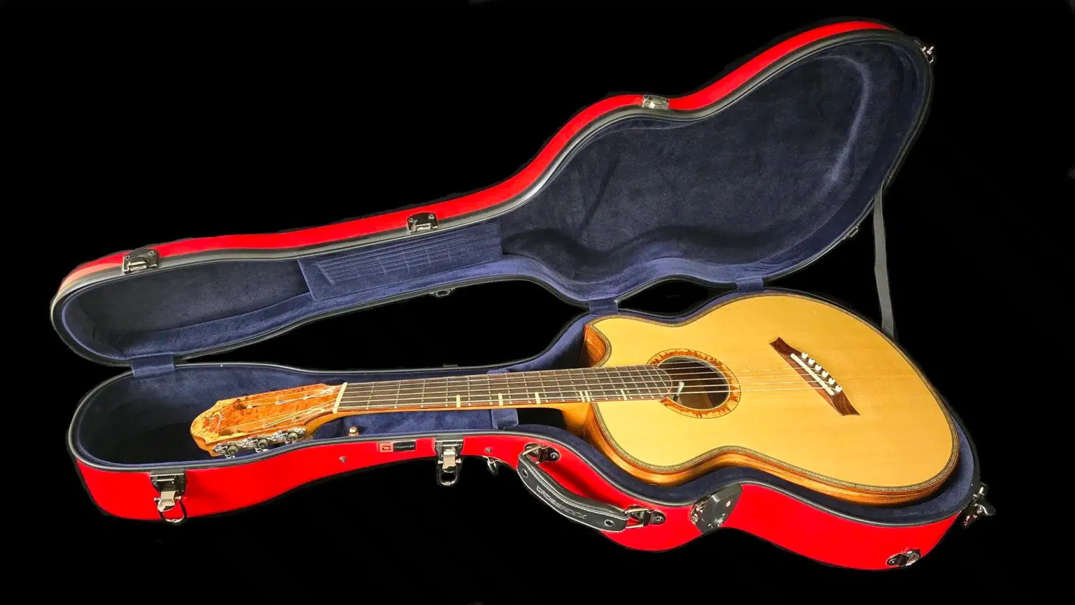 Acoustic guitar resting inside an open red hard shell case with a dark blue plush interior.