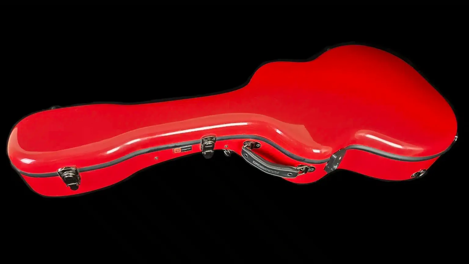 Closed red hard shell guitar case with a contoured shape and black trim.