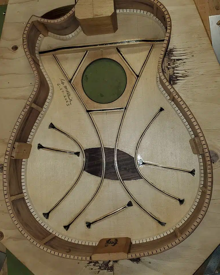 Interior view of an acoustic guitar body showing custom wood bracing and kerfing.