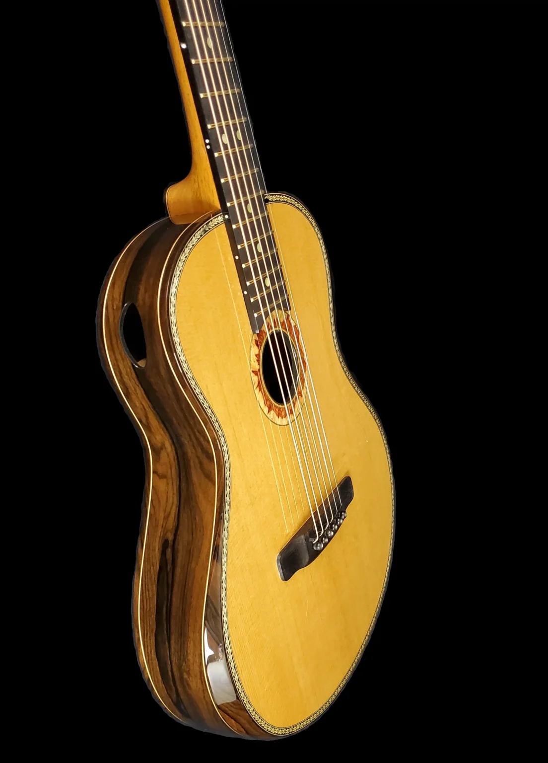 Angled view of an acoustic guitar showing the soundboard, side sound port, and striped wood sides.