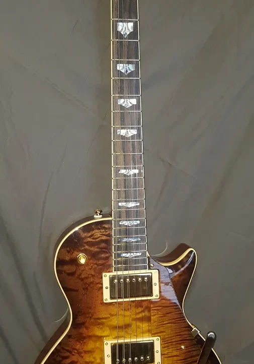 Full-length view of a custom electric guitar with quilted maple top and gold hardware