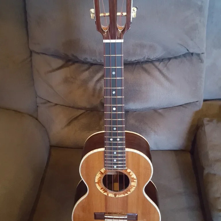 Full view of a handcrafted ukulele with slotted headstock, rosette detail, and natural wood finish