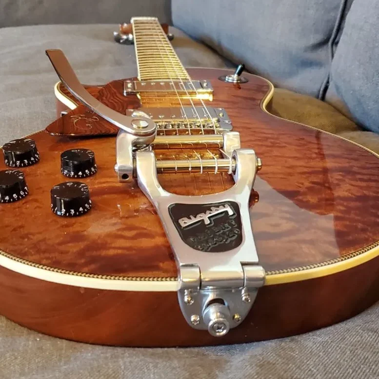 Angled close-up of a custom electric guitar with quilted maple top and Bigsby tremolo