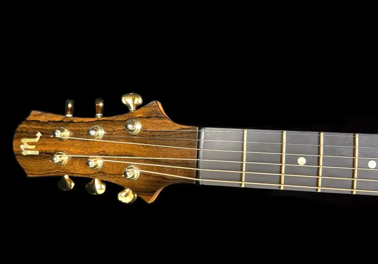 Close-up of a custom ukulele headstock with figured wood grain, gold tuning machines, and the upper fretboard.