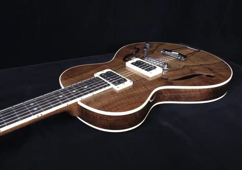 Angled view of a custom semi-hollow electric guitar with figured wood top and dual pickups