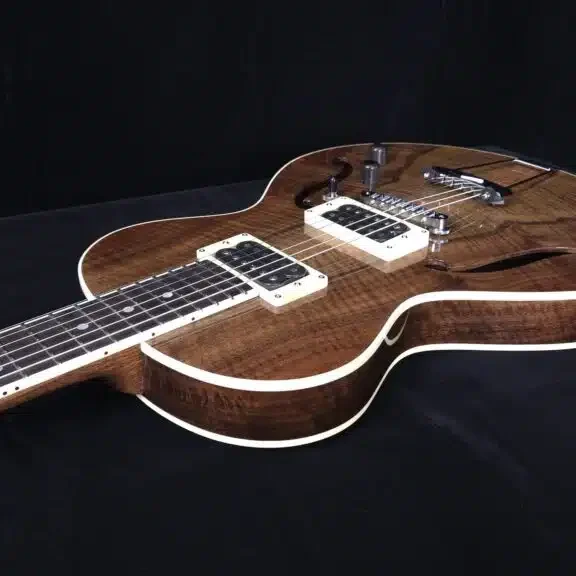 Angled view of a custom semi-hollow electric guitar with figured wood top and dual pickups