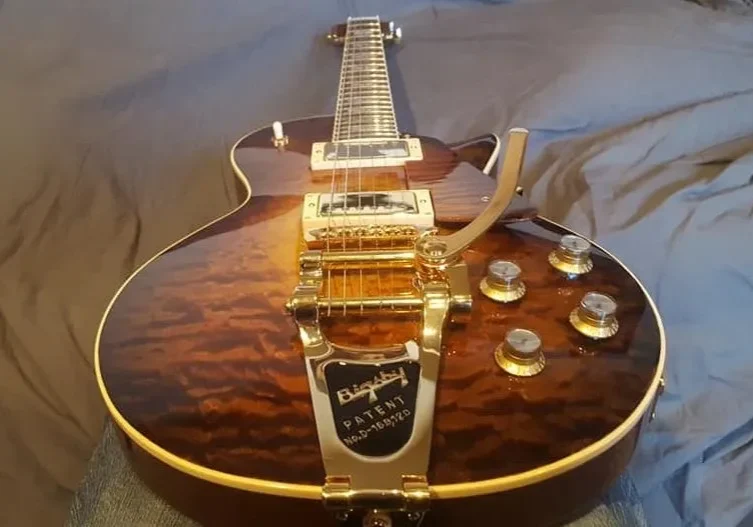 Angled top view of a custom electric guitar with quilted maple top and gold tremolo hardware