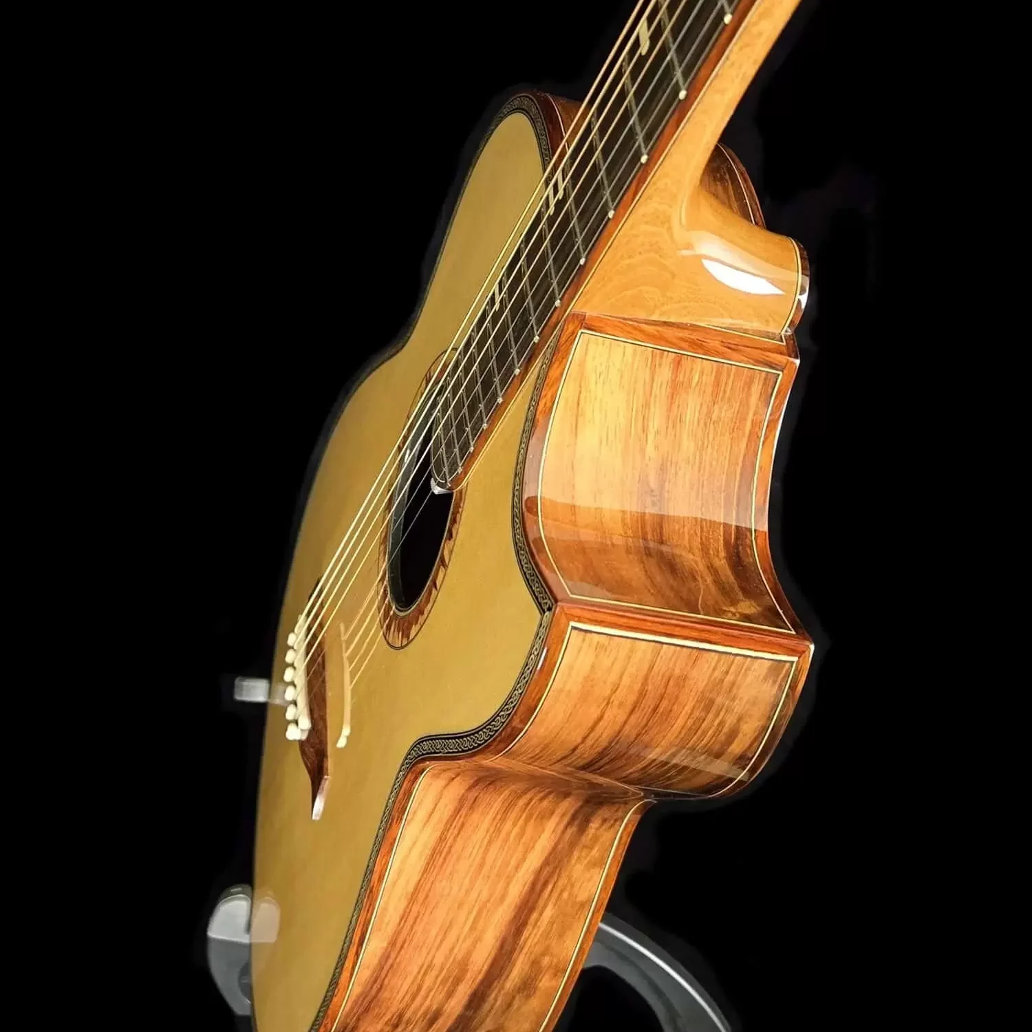 Side angle of a handcrafted acoustic guitar showing layered wood sides and smooth neck joint
