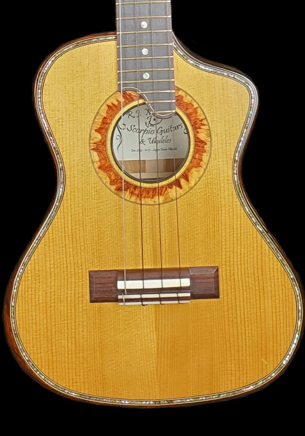 Concert ukulele with light wood top, decorative rosette, and dark wood bridge.